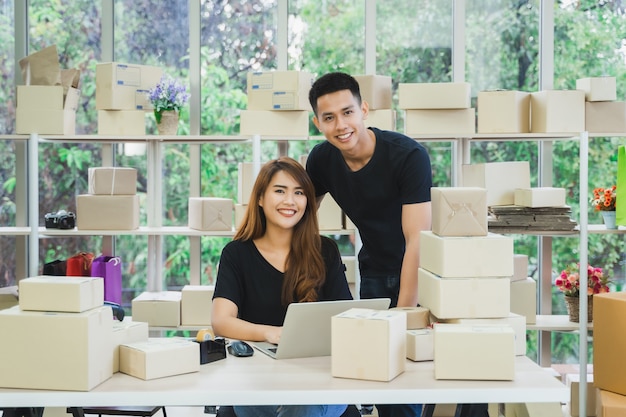 Photo portrait de jeune couple d'affaires asiatiques heureux propriétaire de pme en ligne à la recherche de l'appareil photo
