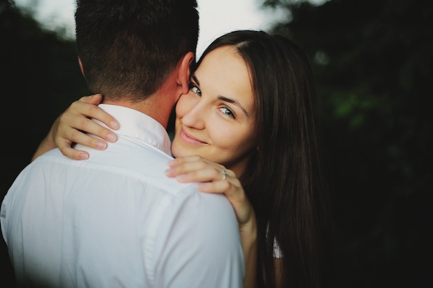 Portrait de jeune couple amoureux étreignent à l'extérieur sur le terrain au coucher du soleil le jour d'été.