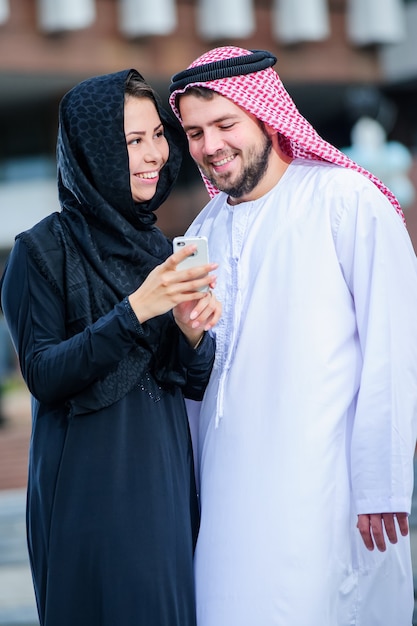 Portrait de jeune couple arabe jouer avec téléphone mobile