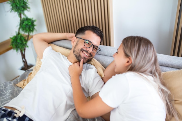 Portrait de jeune couple assis sur le lit et se regarder Attrayant beau nouveau mariage homme et femme en pyjama profiter de l'activité du matin dans la chambre à la maison Concept de relation familiale