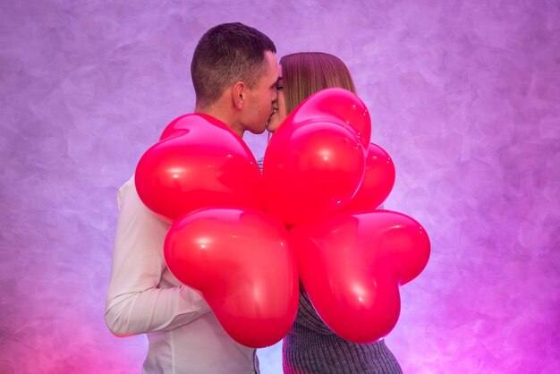 Portrait de jeune couple avec des ballons à air coeur forme rouge. Concept de célébration de la Saint-Valentin