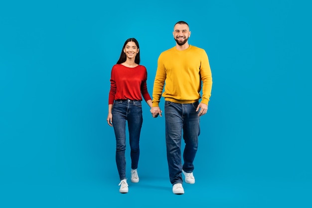 Portrait d'un jeune couple caucasien heureux se tenant par la main et marchant vers la caméra