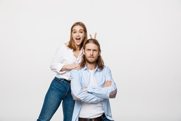 Portrait de jeune couple charmant montrant la paix ou la victoire signe sur fond de studio blanc