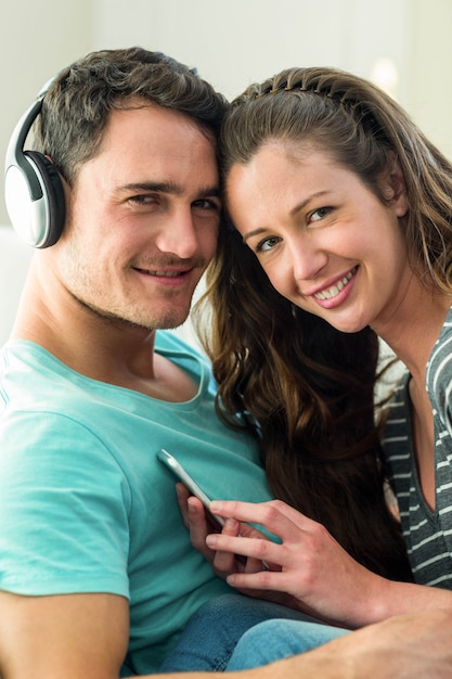 Portrait, de, jeune couple, écoute, musique, sur, téléphone portable, dans, salle de séjour