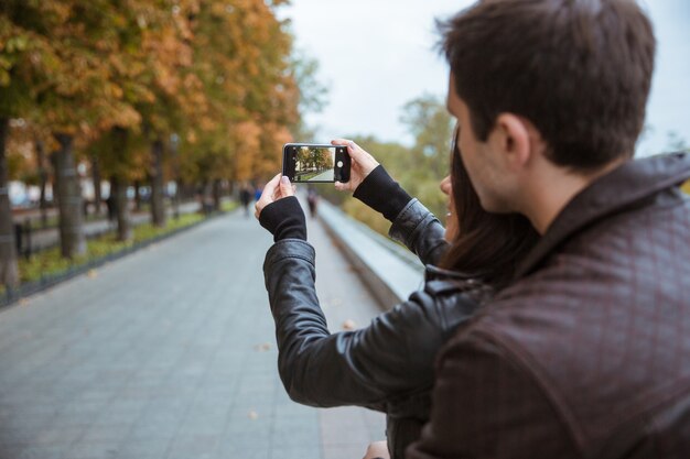 Portrait d'un jeune couple faisant photo sur smartphone du parc automne