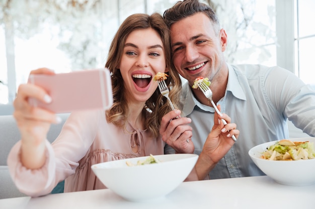 Portrait d'un jeune couple gai prenant un selfie