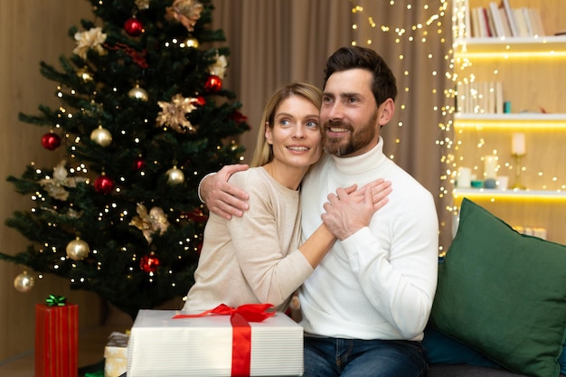 Portrait d'un jeune couple heureux famille jeune homme et femme célébrant les vacances de Noël à la maison