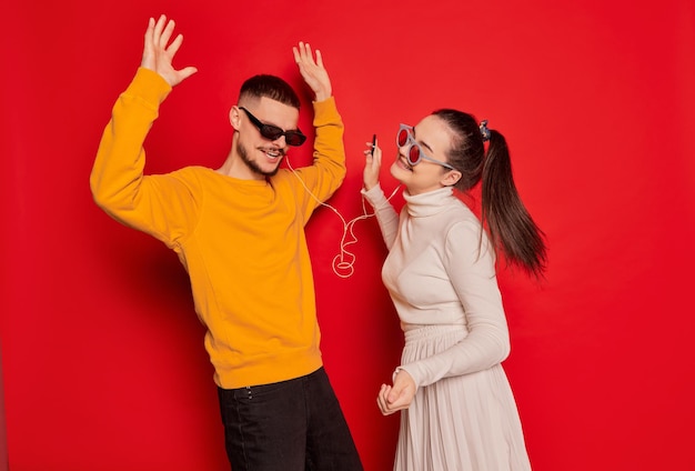 Portrait d'un jeune couple heureux homme et femme dansant joyeusement avec de la musique dans des écouteurs isolés