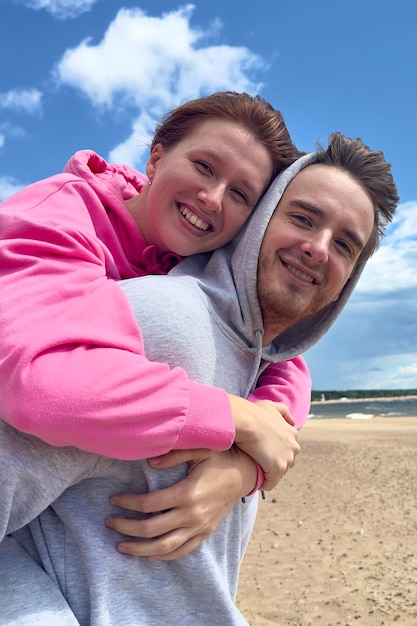 Portrait d'un jeune couple heureux marchant sur la plage s'embrassant l'un l'autre. Le type porte sa petite amie.