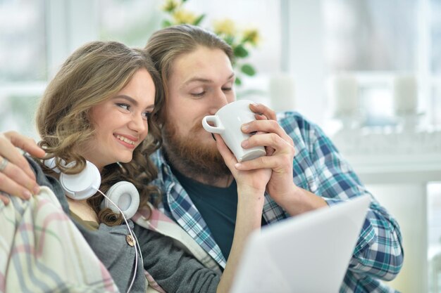 Portrait d'un jeune couple heureux avec un ordinateur portable à la maison