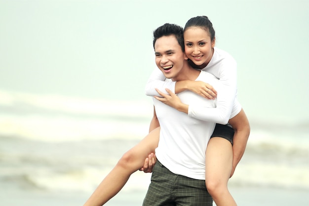 Portrait d'un jeune couple heureux s'amuser sur la plage