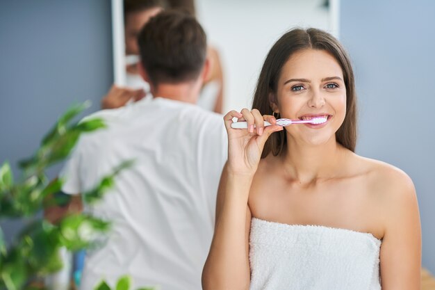 Portrait d'un jeune couple heureux se brosser les dents dans la salle de bain