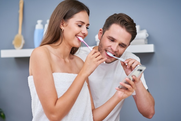 Portrait d'un jeune couple heureux se brosser les dents dans la salle de bain