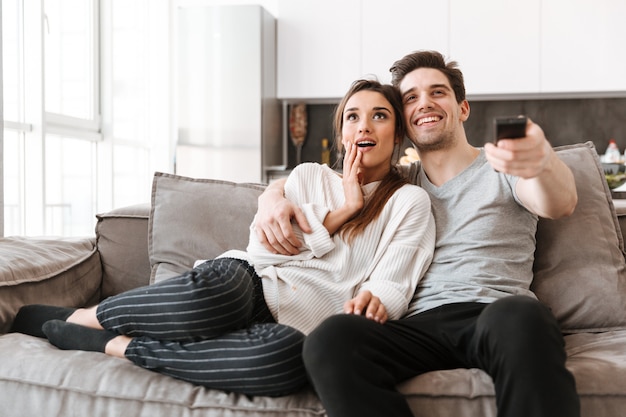 Portrait d'un jeune couple heureux se détendre sur un canapé