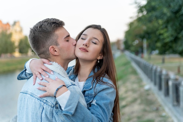 Portrait de jeune couple. Jeune homme embrassant sa petite amie en plein air. Doux câlins sur fond de ville. Un rendez-vous romantique