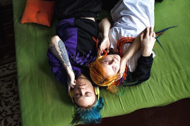 Portrait d'un jeune couple punk tatoué d'une fille et d'un mec aux longs cheveux teints tressés allongés