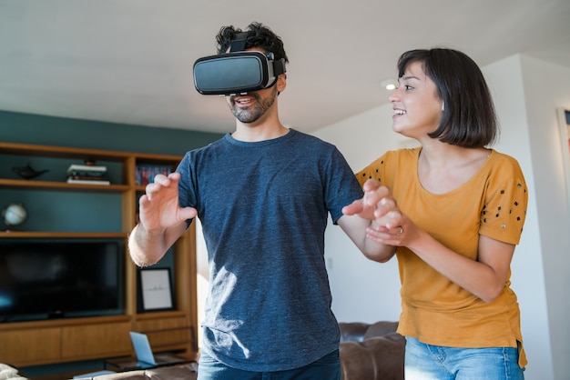 Portrait de jeune couple s'amusant ensemble et jouant à des jeux vidéo avec des lunettes VR tout en restant à la maison. Nouveau concept de mode de vie normal.