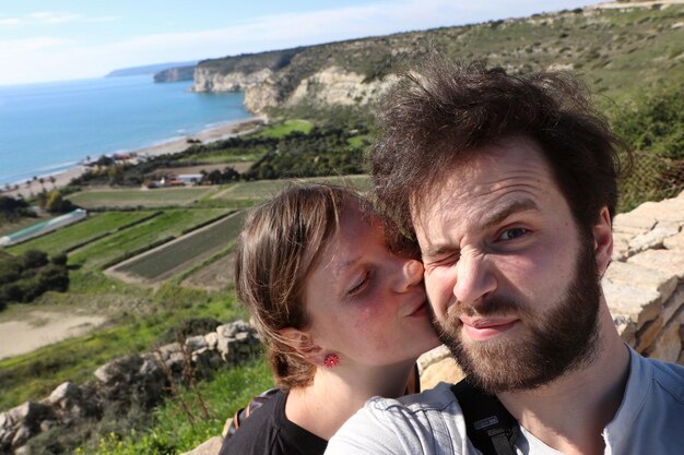 Photo portrait d'un jeune couple s'embrassant alors qu'ils se tiennent contre le champ