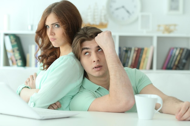 Portrait d'un jeune couple se disputant avec un ordinateur portable à la maison