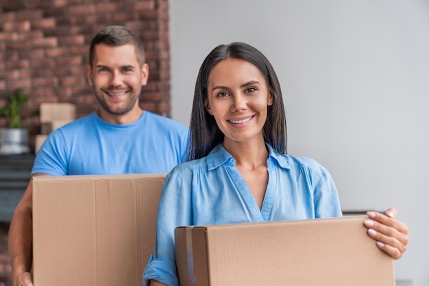 Portrait D'un Jeune Couple Séduisant Déménageant Dans Un Nouvel Appartement Et Tenant Des Boîtes Dans Les Mains