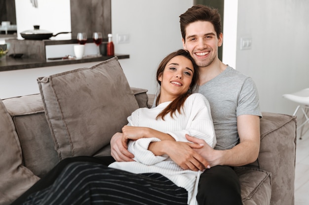 Portrait d'un jeune couple souriant se détendre sur un canapé