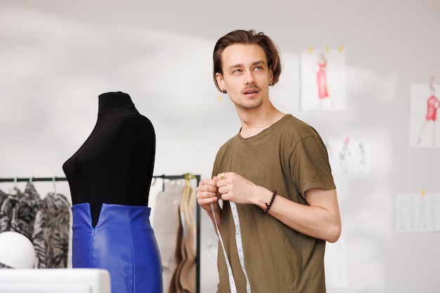 Portrait d'un jeune créateur de mode sur le fond d'un mannequin et d'une machine à coudre