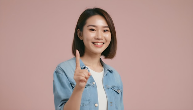 Portrait d'une jeune dame asiatique souriante avec une expression joyeuse montre quelque chose d'étonnant dans l'espace vide