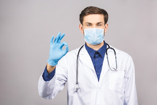 Portrait de jeune docteur en masque et gants bleus signe ok