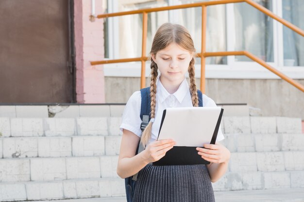 Portrait d'une jeune écolière belle, séduisante et intelligente portant des lunettes dans une chemise blanche faisant une présentation lors d'une conférence en plein air. Elle sourit pendant qu'elle présente