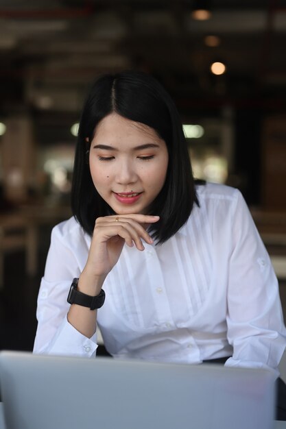 Portrait d'une jeune employée de bureau travaillant sur un ordinateur portable au bureau.