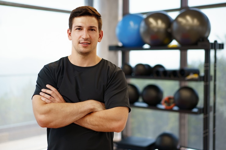 Photo portrait d'un jeune entraîneur de fitness beau dans une salle de sport