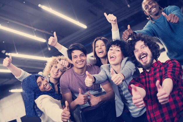 portrait d'une jeune équipe commerciale multiethnique enthousiaste de développeurs de logiciels debout et regardant la caméra tout en célébrant le succès dans un bureau de démarrage moderne