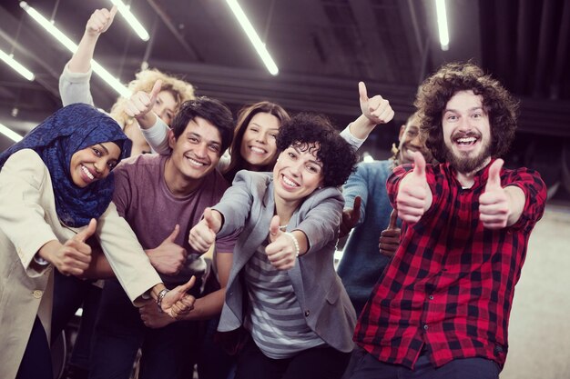 portrait d'une jeune équipe commerciale multiethnique enthousiaste de développeurs de logiciels debout et regardant la caméra tout en célébrant le succès dans un bureau de démarrage moderne