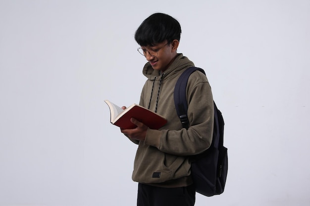 Portrait d'un jeune étudiant asiatique souriant en lisant un livre