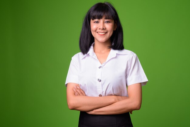 Portrait de jeune étudiant belle femme asiatique contre le mur vert