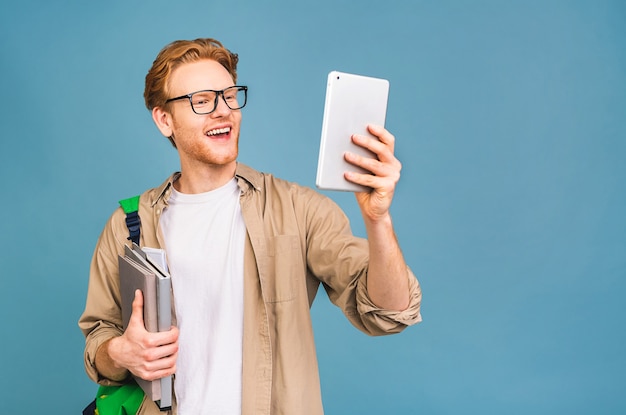 portrait de jeune étudiant souriant heureux debout avec sac à dos et dossiers. à l'aide d'une tablette