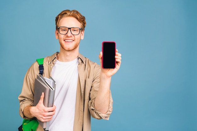 portrait de jeune étudiant souriant heureux debout avec sac à dos et dossiers. à l'aide d'un téléphone portable.