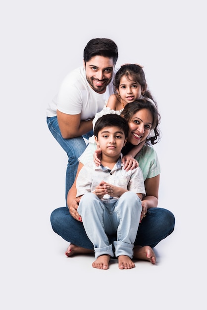 Portrait de jeune famille asiatique indienne de quatre personnes assises sur de la farine blanche sur fond blanc, regardant la caméra