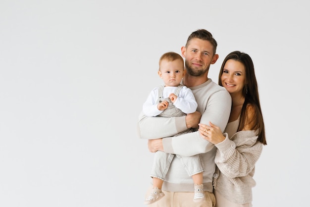 Portrait d'une jeune famille heureuse avec un fils d'un an dans les bras avec un espace de copie