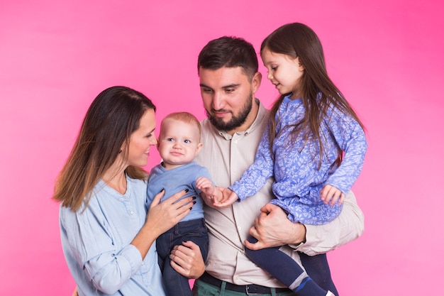 Portrait de jeune famille métisse heureuse sur mur rose.