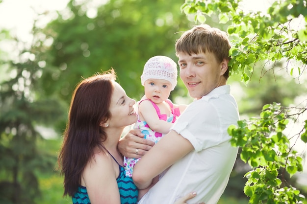 Portrait de jeune famille avec petite fille dans le parc d'été