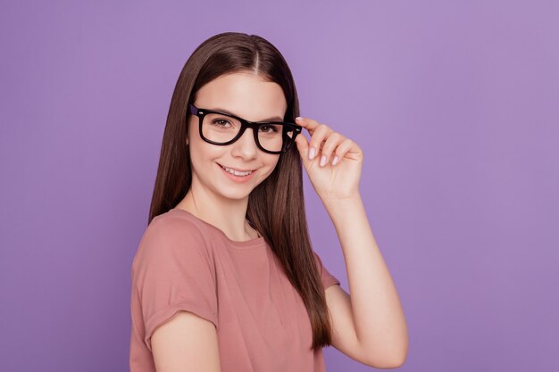 Portrait de jeune femme adolescente créative touchant des mains de lunettes sur fond violet