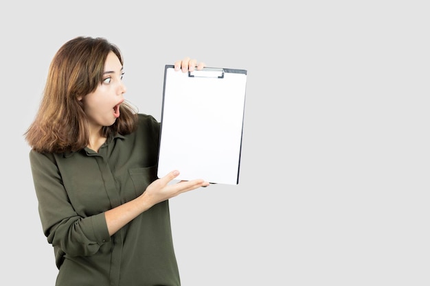 Portrait de jeune femme adorable montrant le presse-papiers vide. photo de haute qualité