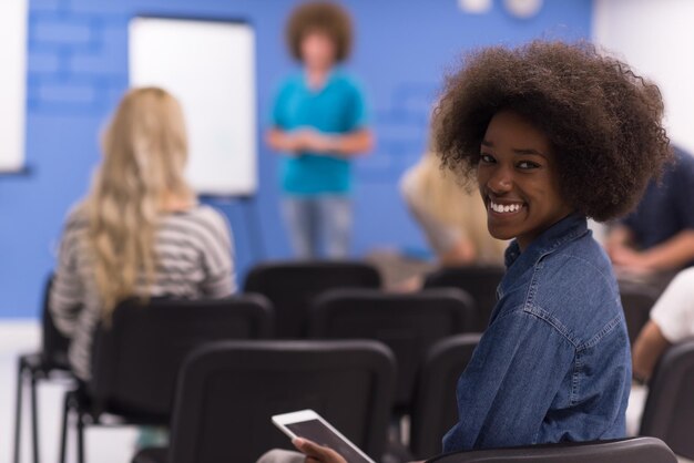 Photo portrait d'une jeune femme d'affaires afro-américaine à l'intérieur d'un bureau de démarrage moderne, équipe en réunion en arrière-plan