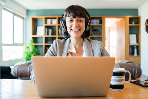 Portrait de jeune femme d'affaires sur appel vidéo avec ordinateur portable et écouteurs