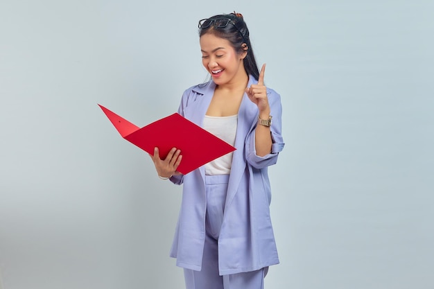 Photo portrait d'une jeune femme d'affaires asiatique joyeuse tenant un dossier de documents et obtient une idée brillante à l'esprit isolée sur fond violet