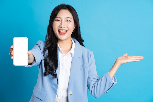 Portrait de jeune femme d'affaires asiatique posant sur fond bleu
