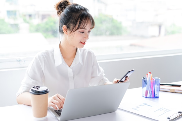 Portrait de jeune femme d'affaires assise et utilisant le téléphone