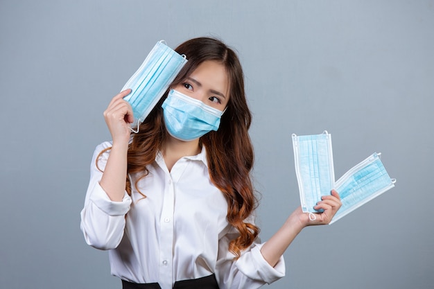 Portrait de jeune femme d'affaires belle portant un masque facial sur une surface grise