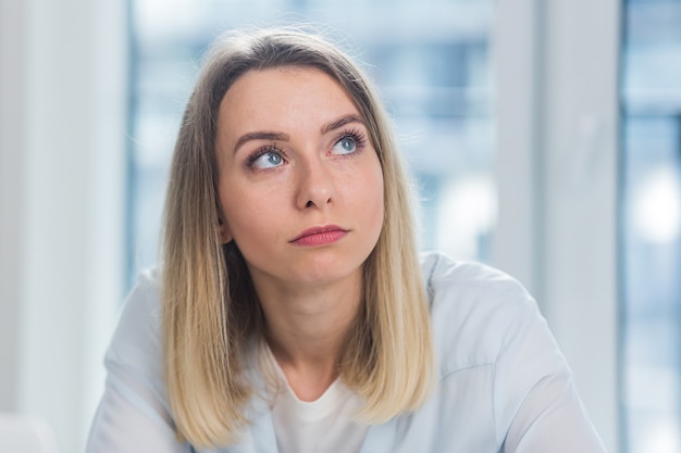 Portrait d'une jeune femme d'affaires blonde adulte regardant la caméra à l'intérieur du bureau